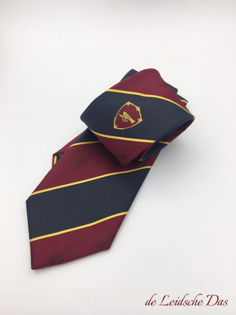 British stripe necktie in red and black with coat of arms in the center and subtle repeats incorporated into the red stripes